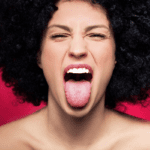 Woman sticking out her tongue - what your tongue reveals about your health