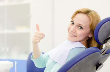 Woman giving a thumbs up from a dental chair
