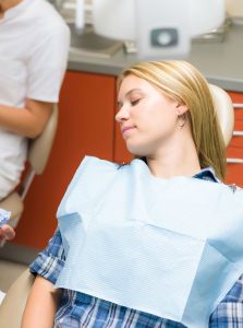 Young blonde woman with eyes closed relaxing in a dental chair - for information on sedation dentistry