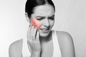 Woman holding her cheek from dental pain